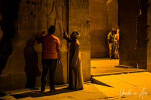An Egyptian guide explaining a relief panel, Kom Ombo Temple after dark