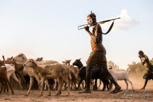 A Kara man with an AK-47 watches a goat herd, Dus Village Ethiopia