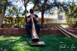 Man in black playing a didgeridoo, Resort Town Square Lawn Stage, Ayers Rock Resort NT Australia.