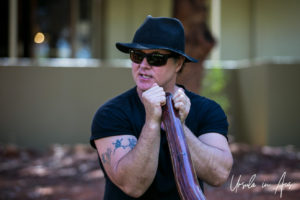 Portrait: Man in black holding a didgeridoo, Ayers Rock Resort NT Australia.