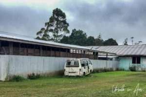Rusting van outside corrugated iron school buildings, Mt Hagen PNG
