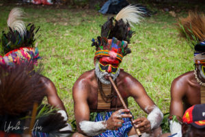 Moikep man in face paint playing a bamboo flute, Mt Hagen, Papua New Guinea