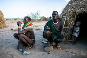 Man and woman squatting outside a Nyangatom home, Omo Valley, Ethiopia