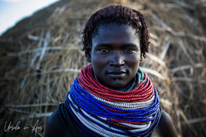 Portrait: Nyangatom Woman in red, blue and white beads, Omo Valley Ethiopia