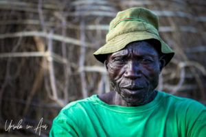 Portrait: Nyangatom man in a green t-shirt and hat, Omo Valley, Ethiopia