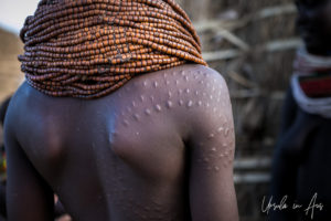 Back view of a Nyangatom woman with scarred shoulder and beads, Omo Valley Ethiopia