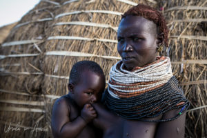 Portrait: Nyangatom woman with an infant suckling, Omo Valley, Ethiopia