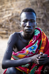 Portrait: Young Nyangatom man in a colourful blanket, Omo Valley, Ethiopia