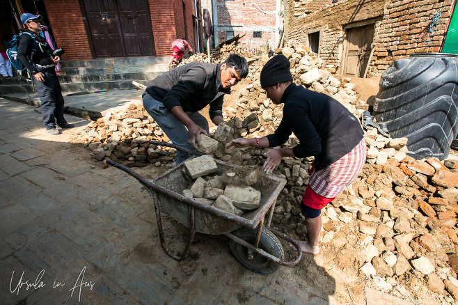Man and woman putting old bricks into a wheelbarrow, Changunarayan, Nepal
