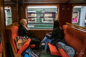 Two women in a train carriage, watching another train pass, Flåmsbana, Norway