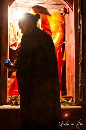 Person silhouetted by the light of a shrine, Varanasi street, India