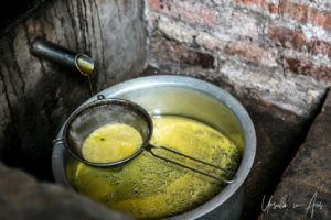 Collecting and straining the fresh-pressed mustard oil, Khokana, Nepal