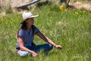 A woman in a hat seated in grass, Top Hut TSS, NSW Australia