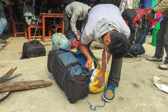 A Nepali porter bundling bags at the start of the Ghorepani trek.