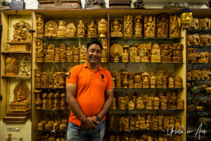 Male shopkeeper in front of shelves of carved rosewood and sandalwood, Pondicherry India