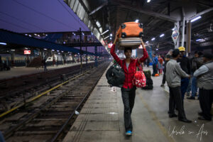 Indian porter with bags on his head, New Delhi Railway Station, India