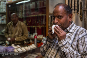 Indian man blowing a conch shell in a shop, Haridwar.