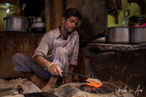 An Indian man sits making chapati on a coal fire, Haridwar.