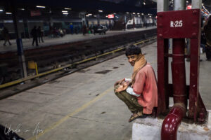 Young man squatting, New Delhi Railway Station, India