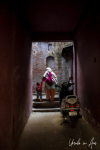 Woman, child, and a scooter in a dark alley, Haridwar India