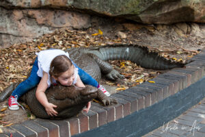 Child on a life-size crocodile sculpture, Taronga Zoo, Sydney, Australia