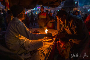 After dark: Hands around a flame on a lamp, Haridwar, India