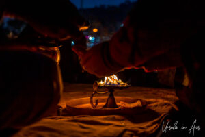 After dark: Hands around a flame on a lamp, Haridwar, India