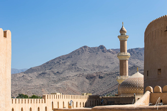 A minaret of Nizwa Fort against the Hajar Mountains, Oman.