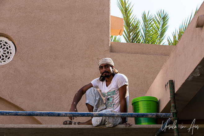 Environmental portrait: Man in white on a scaffold, Nizwa Souq, Oman.