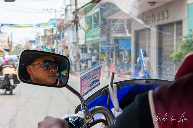 From inside a Tuk Tuk: driver in the mirror and the streets of Nong Khai Thailand