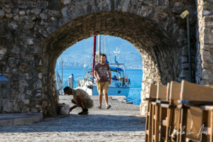 Man walking through an arch, the Venetian port of Nafpaktos, Greece.