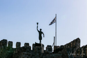 Statue of Georgios Anemogiannis silhouetted on the harbour fortifications, Nafpaktos, Greece.