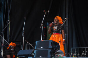 One of Les Aunties, in black and orange, on stage singing, Vancouver Island Musicfest, Comox BC Canada