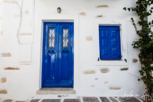 House front with a bright blue door and window shutters, Parikia, Paros Greece.