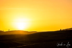 People silhouetted against a Sahara sunset, Erg Chebb, Morocco.