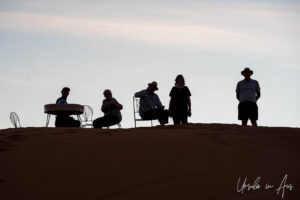 People and metal chairs silhouetted in the Sahara, Erg Chebb, Morocco.