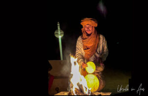 Berber musician warming his goat skin drum on a fire, Erg Chebb, Morocco.