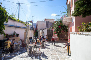 People at courtyard tables in afternoon light, Halki Naxos Greece.