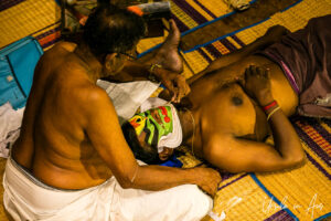 Hands applying a Chutti to Arjunan, Great K V Kathakali Center in Fort Kochi, Kerala India