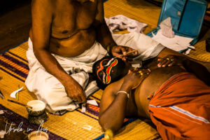 Hands applying white paint to Shiva, Great K V Kathakali Center in Fort Kochi, Kerala India
