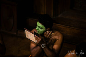 Portrait: Man painting stage makeup on his face, Great K V Kathakali Center in Fort Kochi, Kerala India