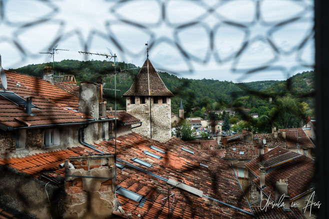 Through a patterned window, over the red-tiled rooftops of Cahors, France.