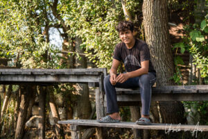 Environmental portrait: smiling young man on a wooden pier, Dal Lake, Jammu and Kashmir, India