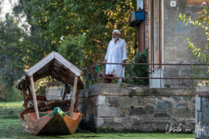 Man in a white shalwar kameez on a private dock, Dal Lake, Jammu and Kashmir, India