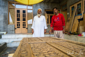 Two men with an unfinished carved walnut door, Dal Lake, Jammu and Kashmir, India