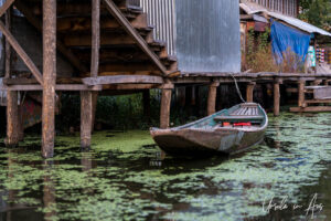 Low wooden boat at the pier of a house or store, Dal Lake, Jammu and Kashmir, India