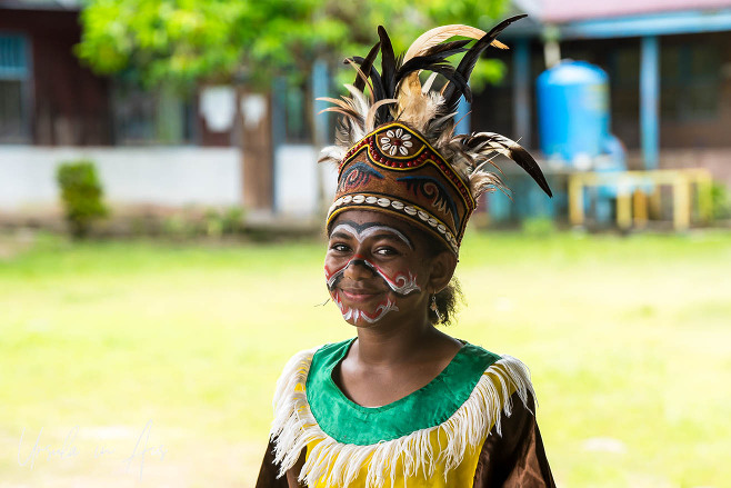 A smiling young West Papuan woman in her bird of paradise paint and headdress, Kwatisore, Indonesia