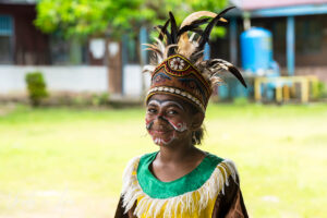 A smiling young West Papuan woman in her bird of paradise paint and headdress, Kwatisore, Indonesia