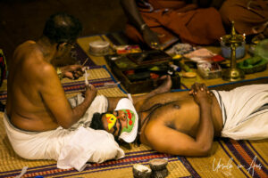 A man applying paste to another man's face, Kerala Kathakali Centre, Fort Kochi, India