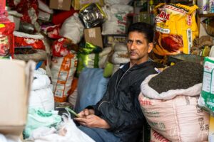 Man sitting surrounded by bags of spice, Srinagar Nowhatta, Jammu and Kashmir, India.